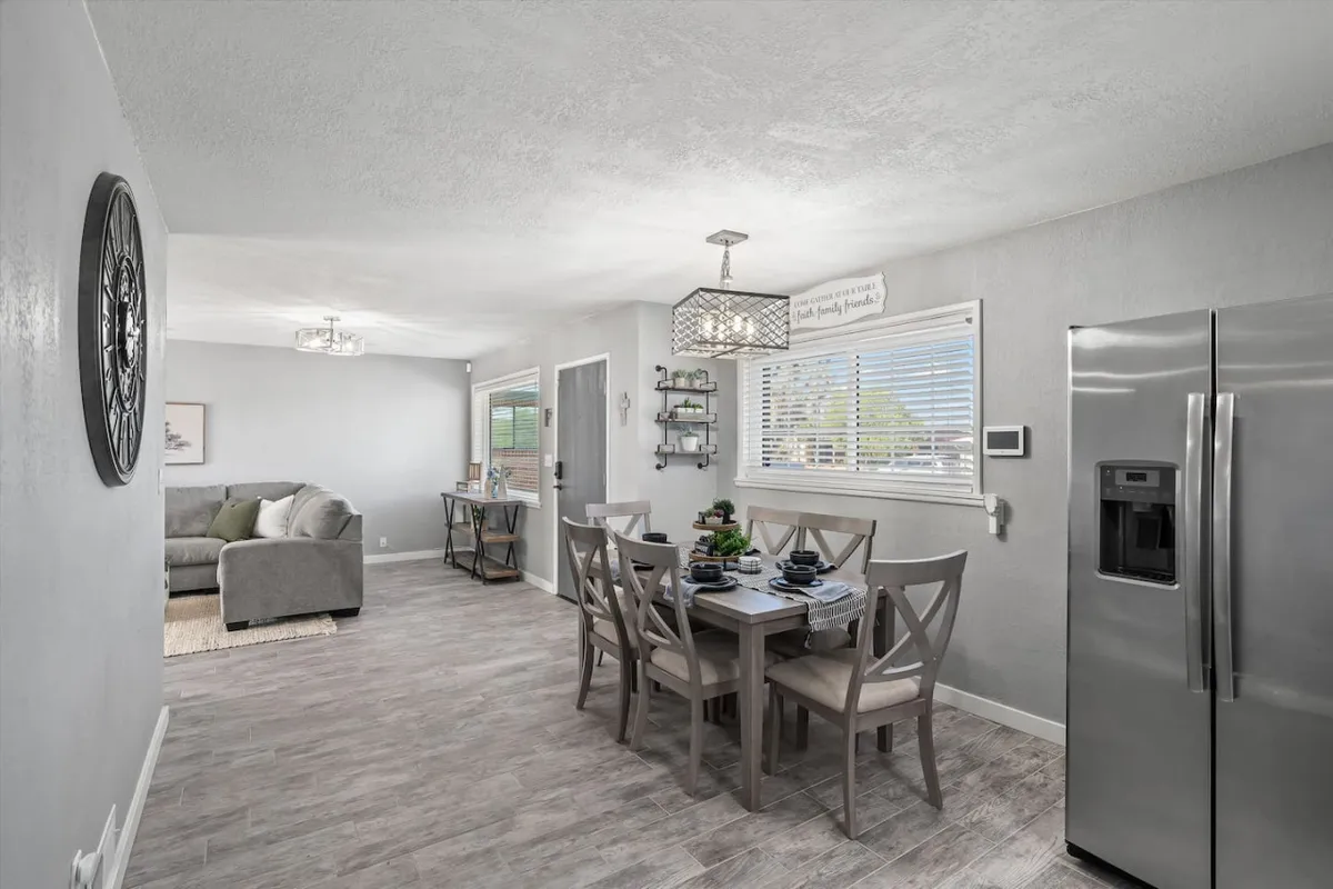 This image presents a dining table set for a meal, with modern kitchen appliances in view and a comfortable living area nearby. The ambiance is welcoming and cozy, emphasizing the dining space as a hub for meals and celebrations.