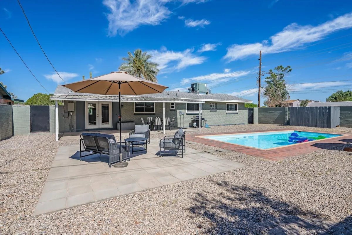 This scene features a relaxing poolside patio area with outdoor seating and an umbrella, perfect for dining or lounging. The space is inviting and fully integrated into the desert landscape, with privacy and tranquility emphasized by the layout.