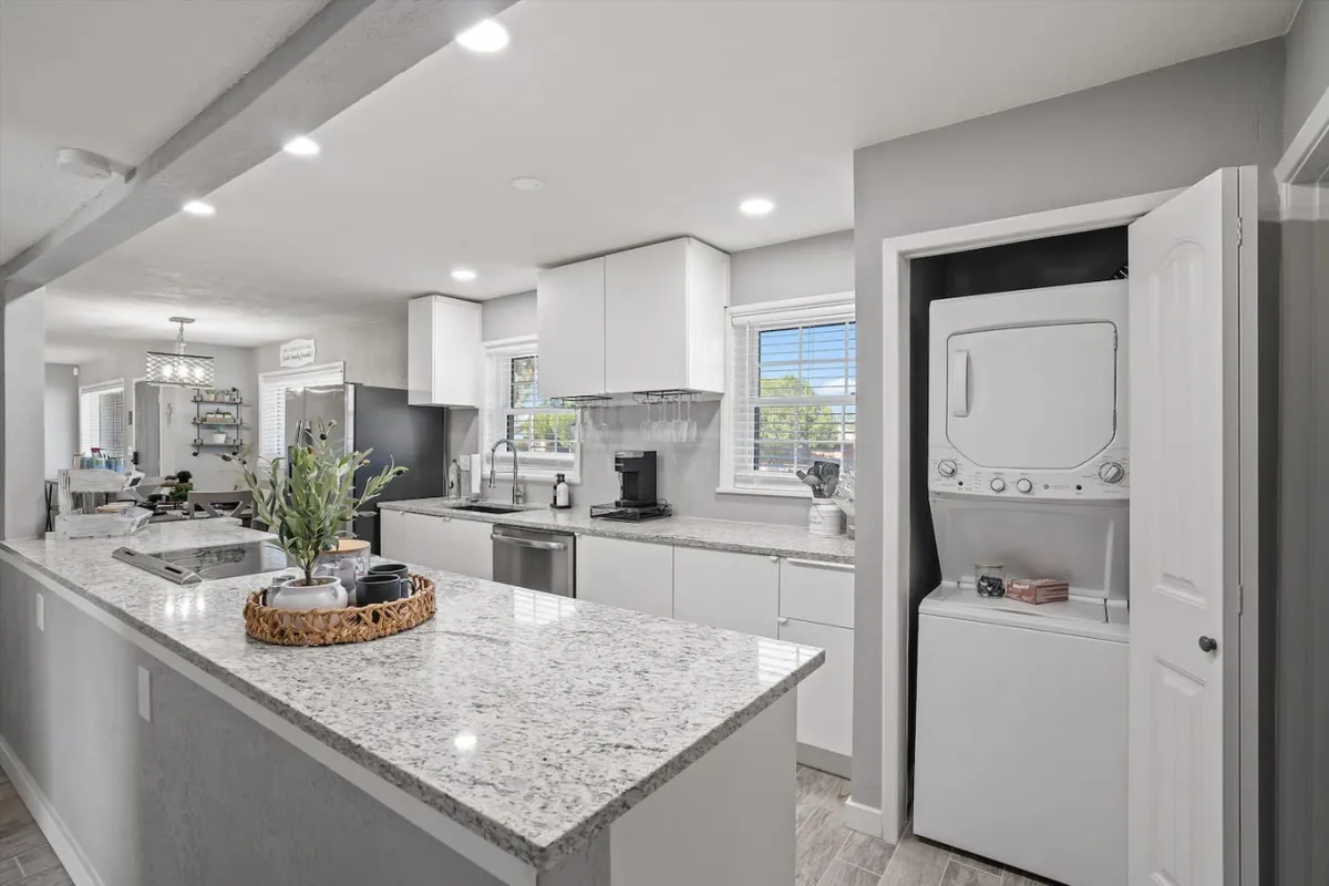 This image presents a bright, modern kitchen with a prominent granite countertop, stainless steel appliances, and a central kitchen island. The arrangement invites collaborative meal prep, and the open layout hints at a space that encourages conversation and togetherness. Warm lighting and subtle decor touches suggest a welcoming atmosphere ideal for both daily routines and special occasions.