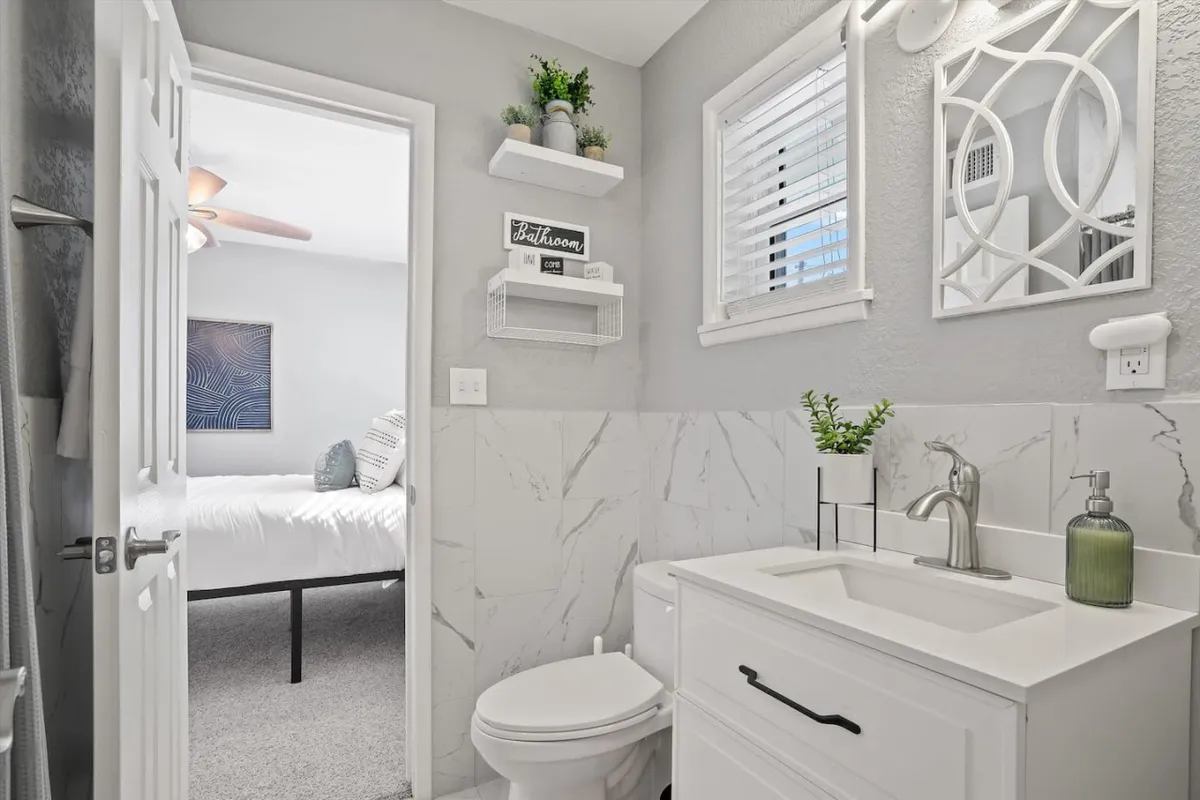 A modern bathroom featuring a white vanity, a large mirror, and a spacious shower area. The clean lines and neutral tones create an inviting and serene space, perfect for refreshing morning routines or unwinding after a busy day.